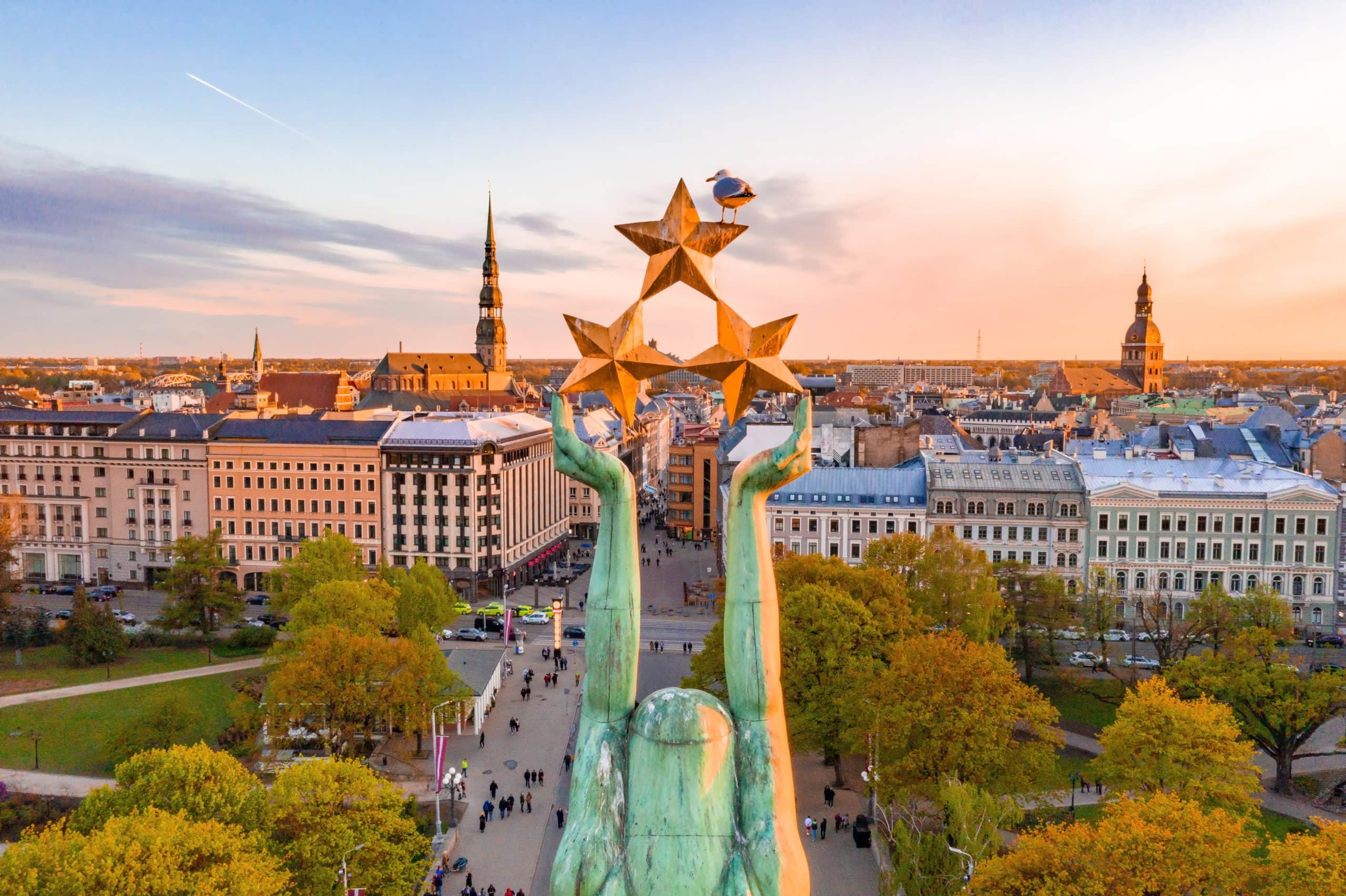 Riga Freedom Monument with three gold stars overlooking the old town skyline at sunset, Latvia — the Baltics