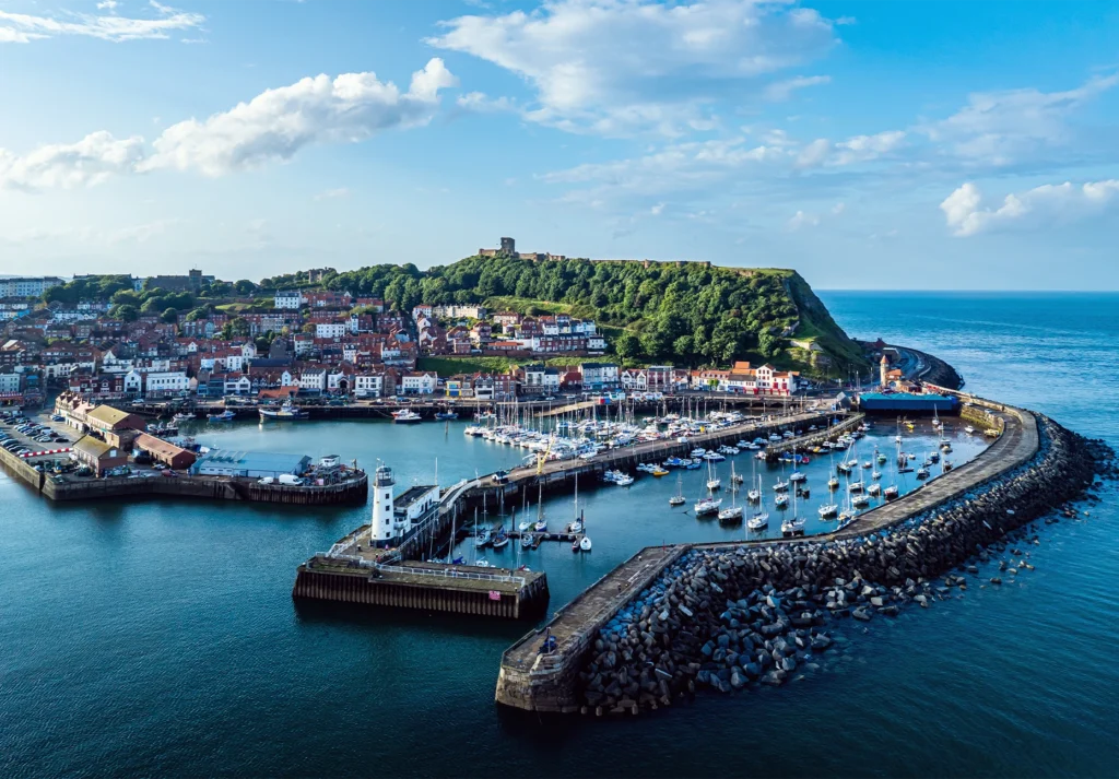 Yachts fill Scarborough’s harbor below the castle headland, with a lighthouse on the pier