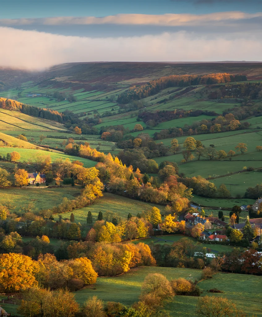 Golden autumn trees and patchwork fields fill the Rosedale valley beneath low cloud