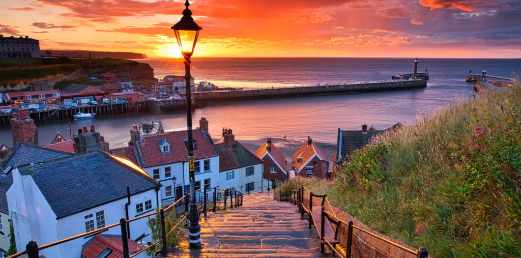 Sunset over Whitby harbor seen from the 199 Steps, with lamppost and red rooftops