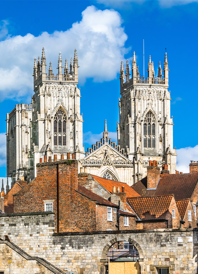 The twin Gothic towers of York Minster rise above brick rooftops and the city walls