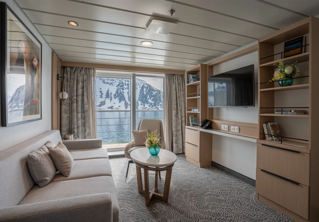 Sofa, armchair, and desk in a suite with a picture window framing snowy cliffs