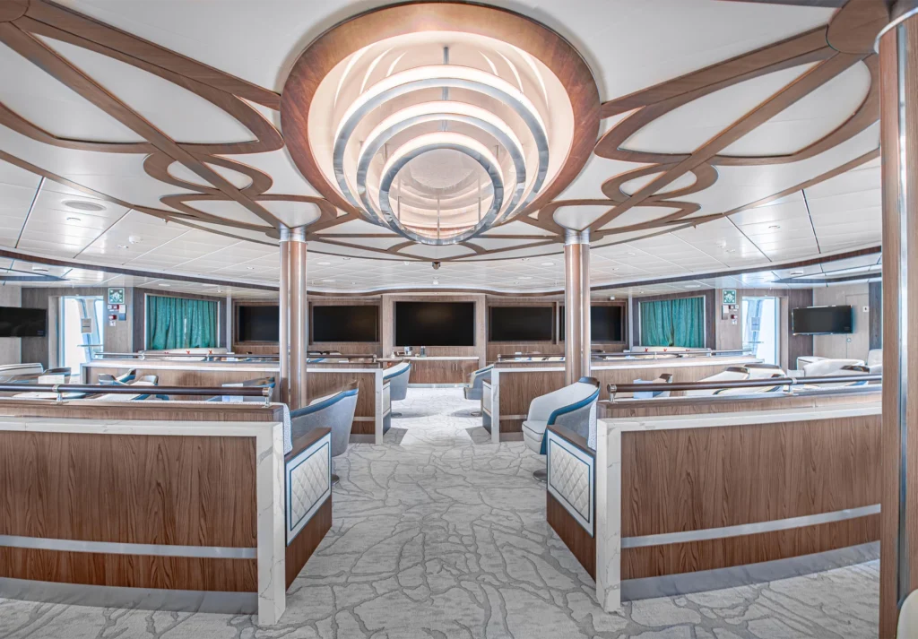 Tiered seating with swivel chairs facing a bank of screens beneath a curved ceiling feature