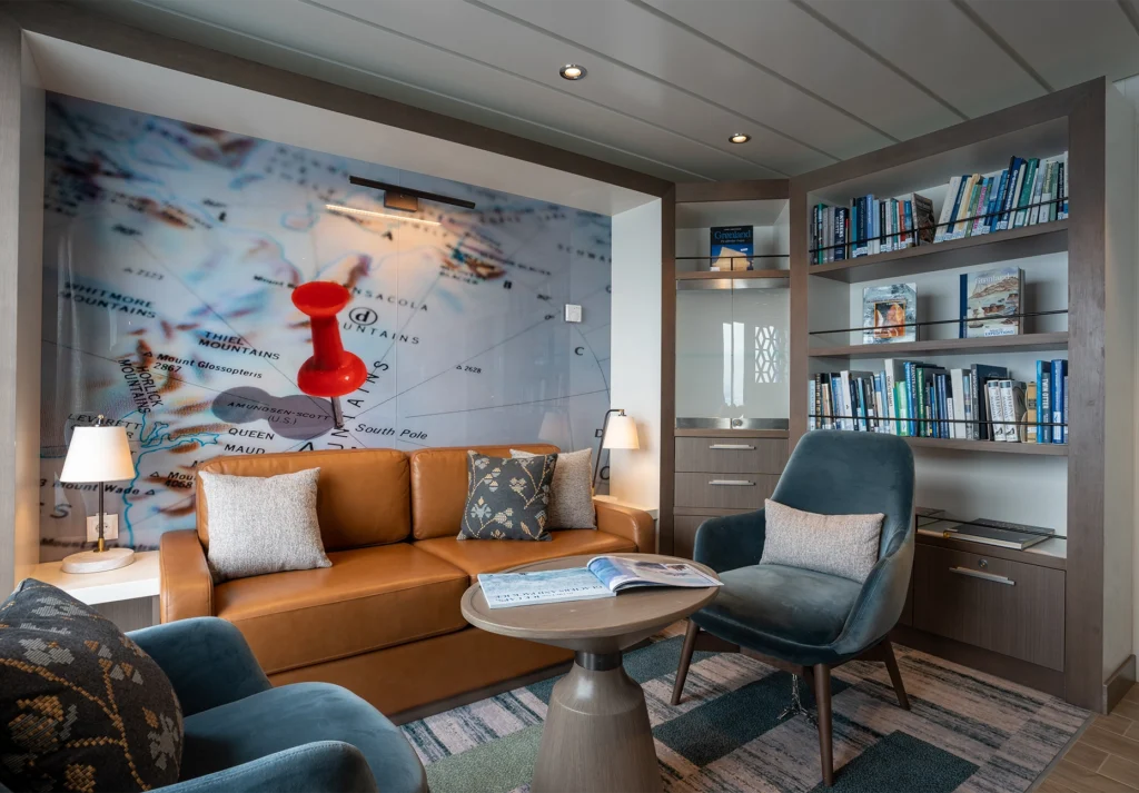 Tan leather sofa and armchairs beside bookshelves and a large map mural with red pin
