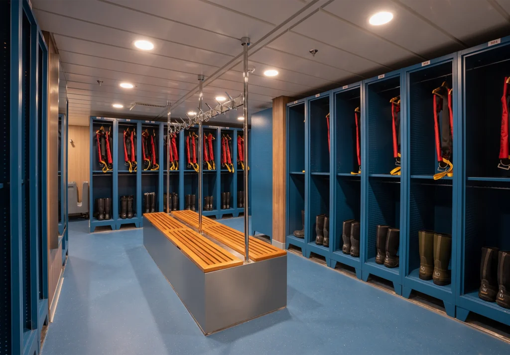 Blue lockers holding rubber boots and red lifejackets around a wooden bench