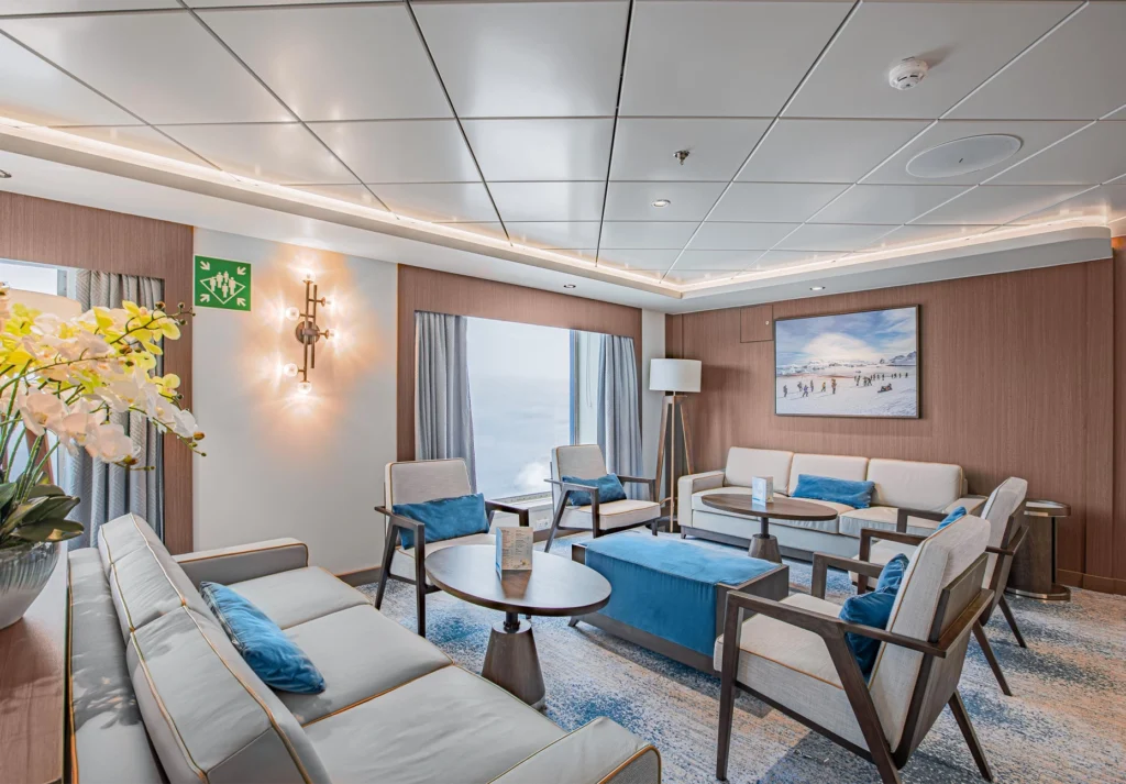 Sofas and armchairs with blue cushions arranged around low tables in a paneled lounge