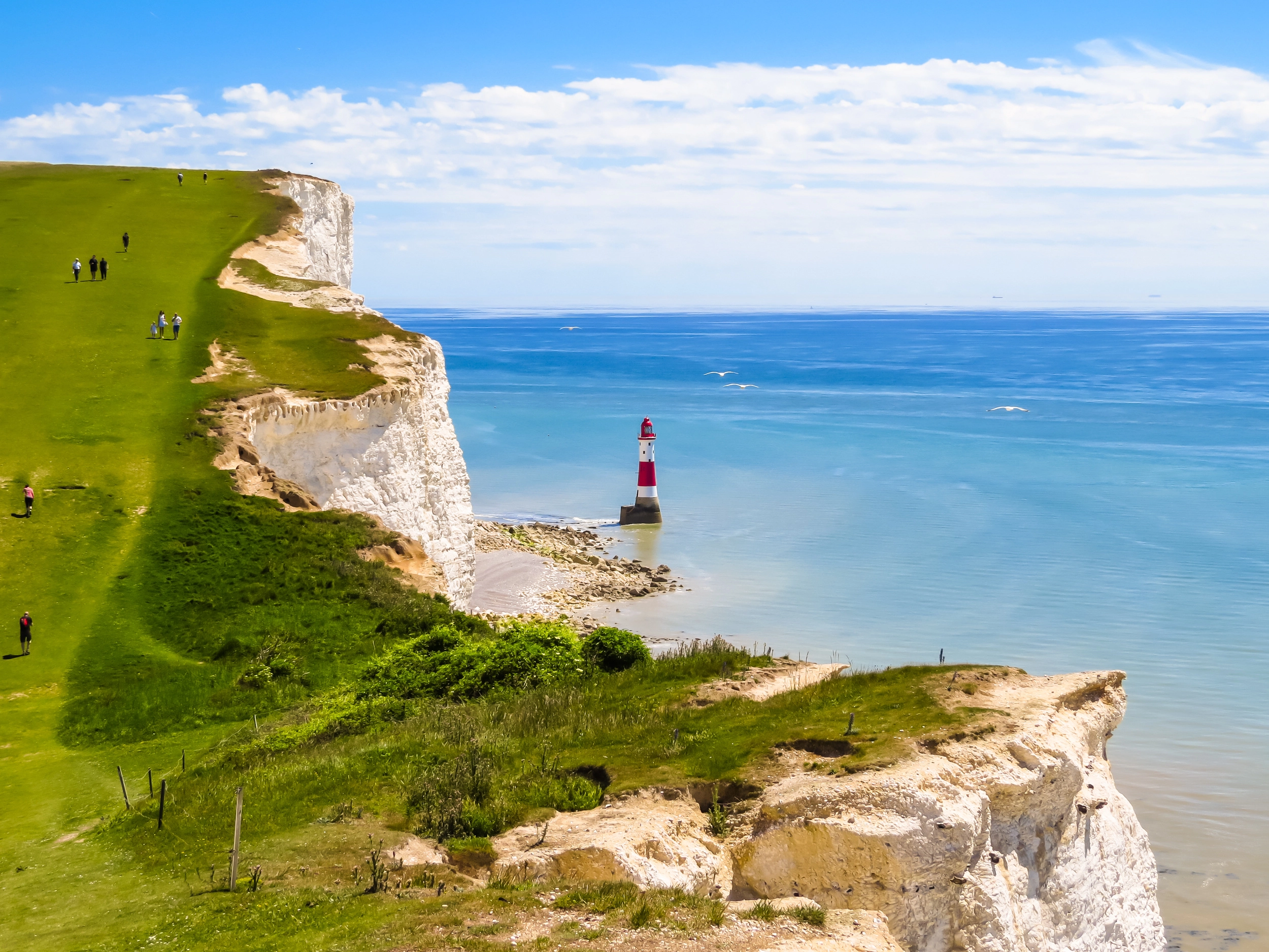People hiking the white cliffs of Dover and lighthouse