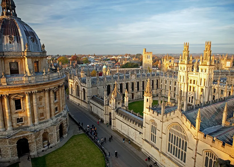 Elevated view of Oxford's skyline with the Radcliffe Camera dome, All Souls College spires, and the historic dreaming spires bathed in golden afternoon light